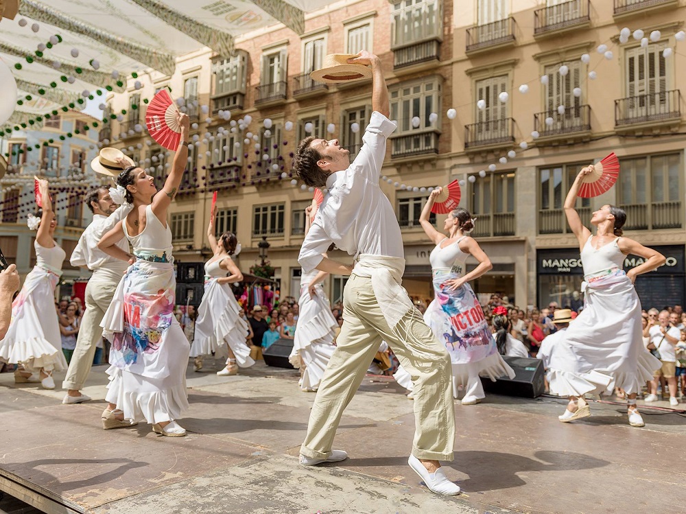 A bustling scene at the Real de la Feria at night, showcasing a variety of 'casetas' or large tents, amusement rides, and food stalls, reflecting the carnival-like atmosphere of the festival.