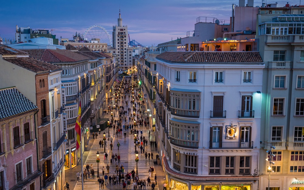 Aerial view of the bustling Larios Street in Malaga, illuminated under the evening sky.