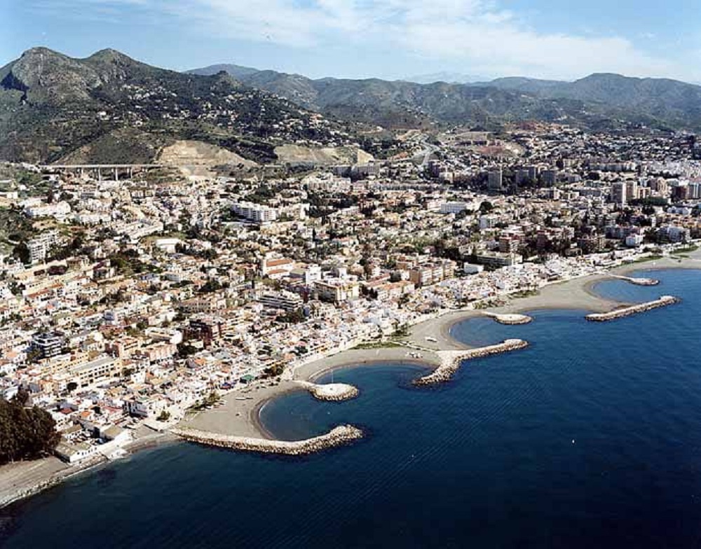 A view of Pedregalejo beach with traditional and modern Andalusian houses in the background.
