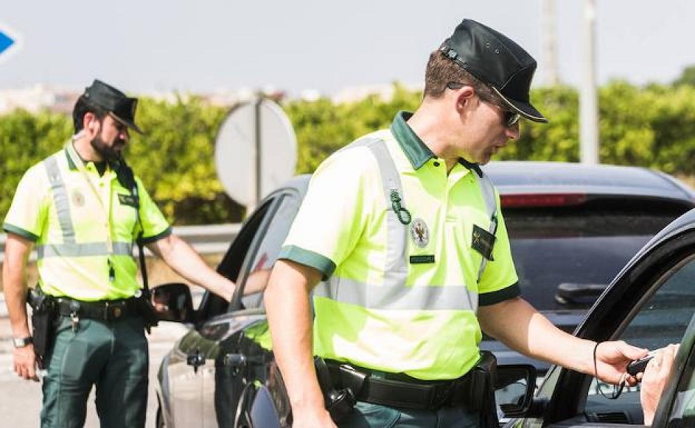 Image of Spanish police officers conducting a traffic stop, a common scenario for enforcing traffic laws and issuing fines for violations, emphasizing the importance of adhering to driving regulations for safety.