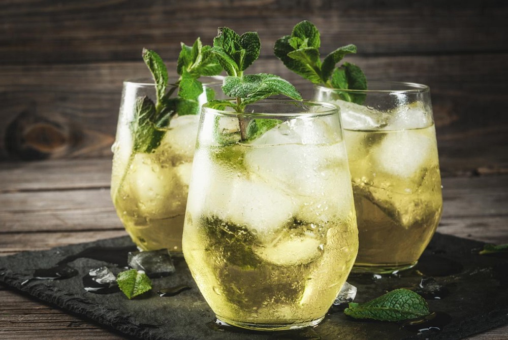 Chilled glass of Rebujito garnished with fresh mint leaves, set against a backdrop of a lively Andalusian festival.