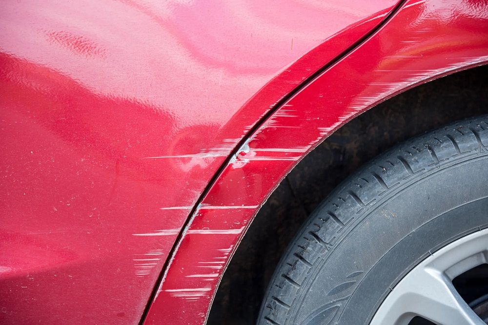 A red car with scratches as example for an exterior inspection when buying a car in Spain.